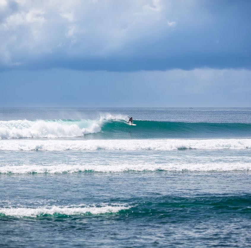 Surfer catches wave at Serangan in Bali, Indonesia