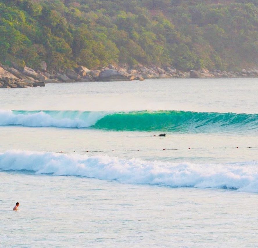 A wave and surfers surfing in Phuket, Thailand