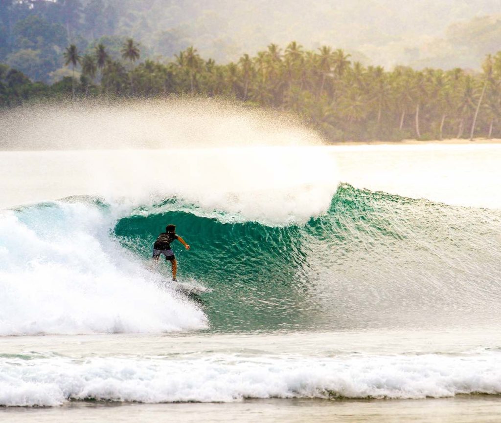 Man riding a wave at Mentawai surf spot in Indonesia