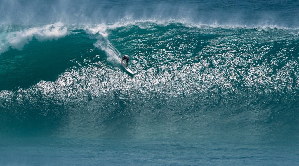 Surfer riding huge wave at Uluwatu - best surf spots in Bali, Indonesia