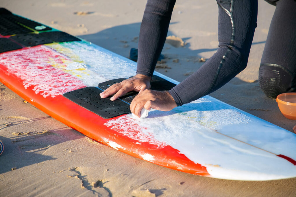 man waxing surfboard